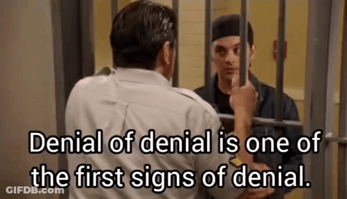 A Man Is Standing In A Jail Cell With A Prisoner Behind Bars . GIF