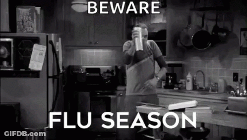 A Man Is Standing In A Kitchen Drinking From A Cup And Talking About Flu Season . GIF