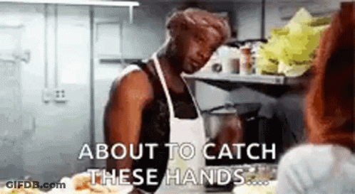 A Man Is Standing In A Kitchen Talking To A Woman . GIF
