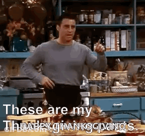 A Man Is Standing In A Kitchen With His Hands On His Hips And Pointing . GIF