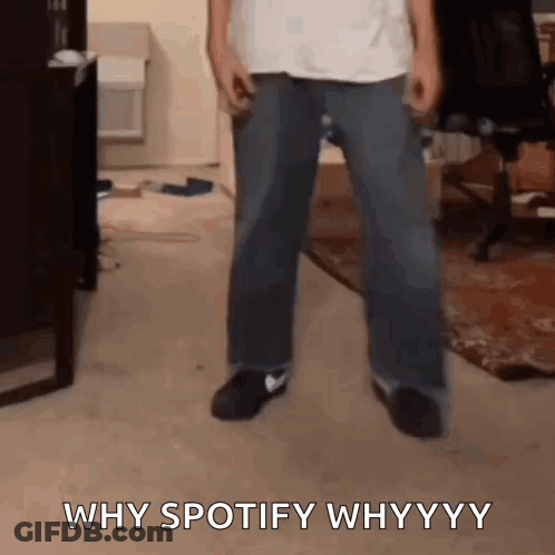 A Man Is Standing In A Living Room With The Words `` Why Spotify Why Yy '' Written On The Floor . GIF