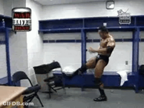 A Man Is Standing In A Locker Room Kicking A Chair In The Air . GIF