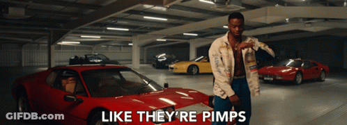 A Man Is Standing In A Parking Garage With Cars And The Words Like They 'Re Pimps On The Bottom GIF