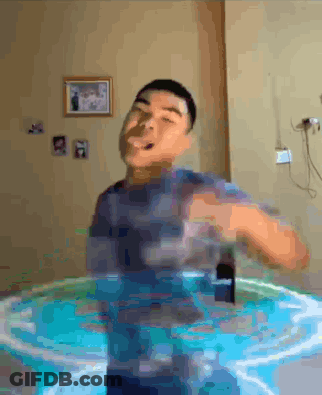 A Man Is Standing In A Pool Of Water With A Cell Phone In His Hand . GIF