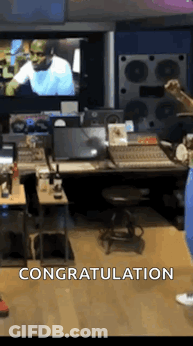 A Man Is Standing In A Recording Studio In Front Of A Large Screen . GIF