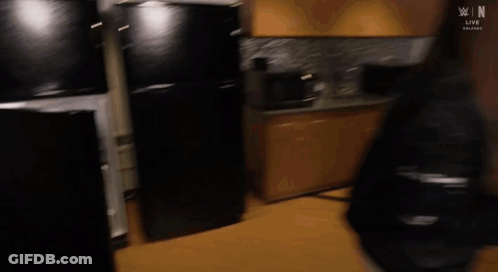 A Man Is Standing In A Refrigerator Looking Inside . GIF