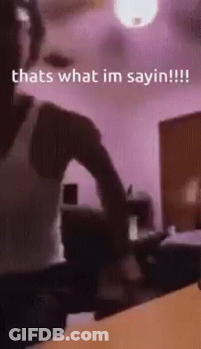 A Man Is Standing In A Room With A Ceiling Fan And A Purple Wall . GIF