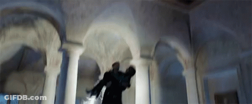 A Man Is Standing In A Room With Arches And Columns Holding A Gun . GIF