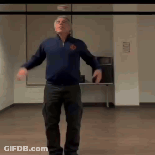 A Man Is Standing In A Room With His Arms Outstretched . GIF
