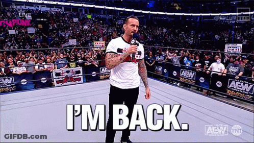 A Man Is Standing In A Wrestling Ring Holding A Microphone And Says I 'M Back GIF