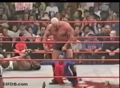 A Man Is Standing In A Wrestling Ring With A Crowd Watching . GIF