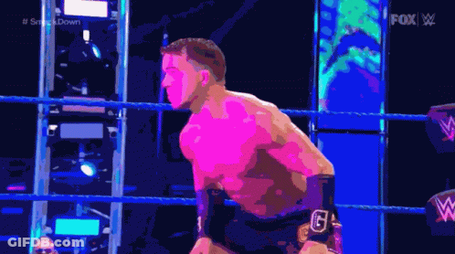 A Man Is Standing In A Wrestling Ring With A Fox Logo Behind Him GIF