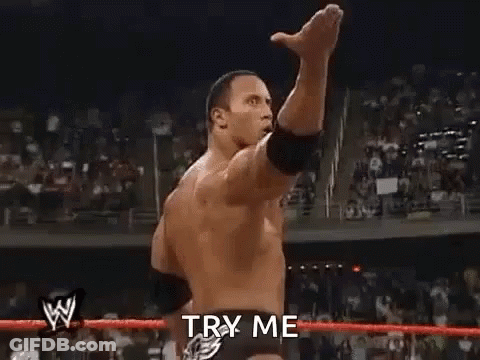 A Man Is Standing In A Wrestling Ring With His Fist In The Air And Says `` Try Me '' . GIF