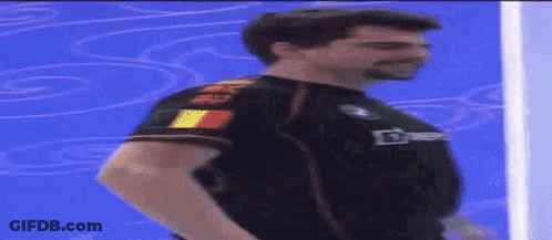 A Man Is Standing In Front Of A Blue Wall Wearing A Black Shirt That Says ' Bmw ' On It GIF