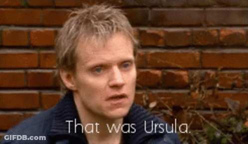 A Man Is Standing In Front Of A Brick Wall And Says That Was Ursula . GIF