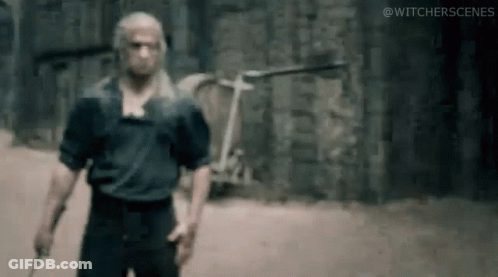 A Man Is Standing In Front Of A Brick Wall Holding A Knife . GIF