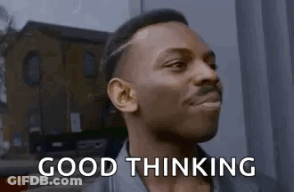 A Man Is Standing In Front Of A Building And Smiling . GIF