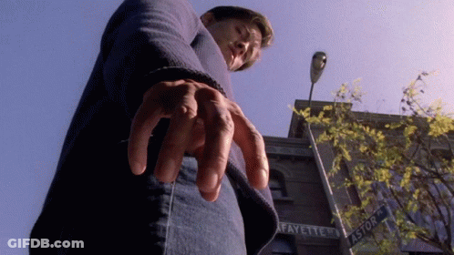 A Man Is Standing In Front Of A Building That Says Fayette On It GIF