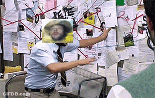 A Man Is Standing In Front Of A Bulletin Board With A Picture Of A Man In A Cowboy Hat On It . GIF