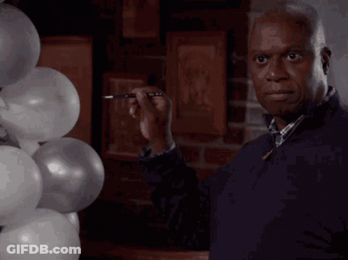 A Man Is Standing In Front Of A Bunch Of Balloons GIF