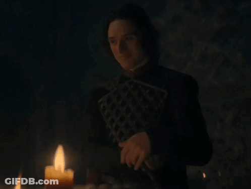 A Man Is Standing In Front Of A Candle In The Dark GIF
