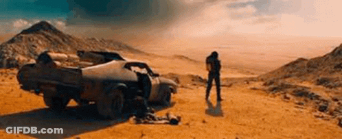 A Man Is Standing In Front Of A Car In The Desert . GIF