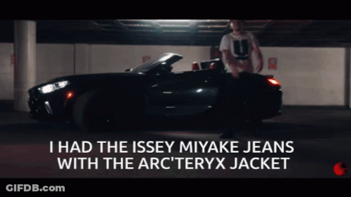 A Man Is Standing In Front Of A Car With The Words I Had The Issey Miyake Jeans With The Arc Teryx Jacket Below Him GIF