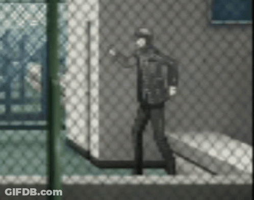 A Man Is Standing In Front Of A Chain Link Fence In A Room . GIF