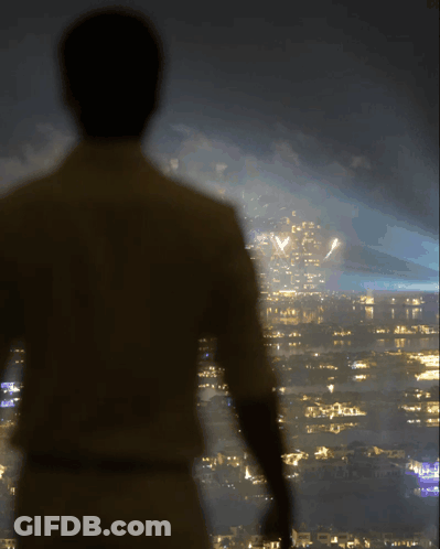 A Man Is Standing In Front Of A City Skyline At Night GIF