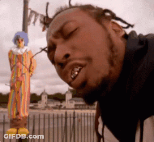 A Man Is Standing In Front Of A Clown Statue With His Eyes Closed GIF