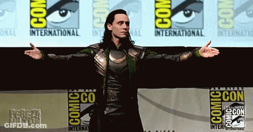 A Man Is Standing In Front Of A Comic Con Banner GIF