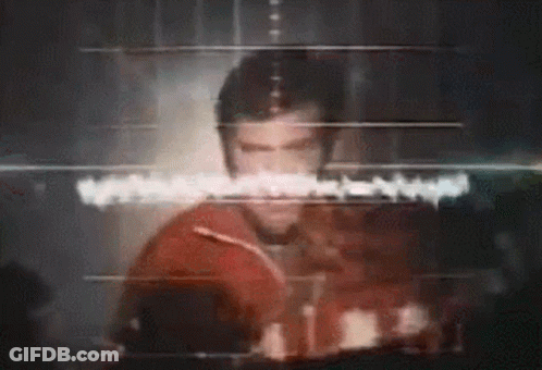 A Man Is Standing In Front Of A Computer Screen With A Heartbeat Monitor . GIF