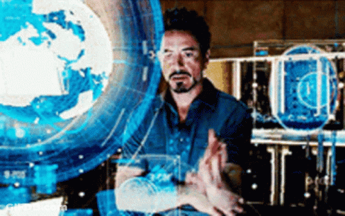 A Man Is Standing In Front Of A Computer Screen . GIF