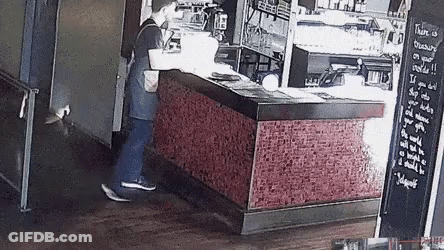 A Man Is Standing In Front Of A Counter In A Restaurant With A Sign On The Wall That Says Family On Your Shoulder GIF