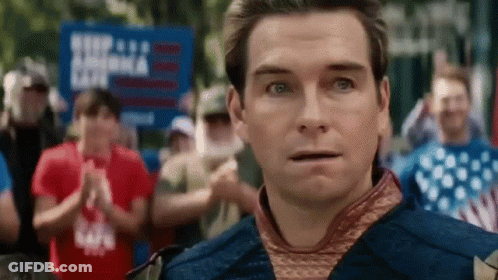 A Man Is Standing In Front Of A Crowd Of People And Looking At The Camera With A Surprised Look On His Face . GIF