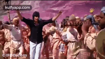 A Man Is Standing In Front Of A Crowd Of People Dancing . GIF