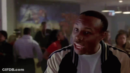 A Man Is Standing In Front Of A Crowd Of People In A Room . GIF
