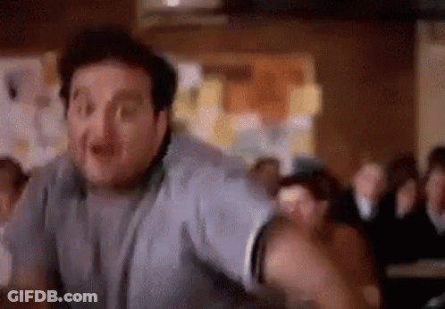 A Man Is Standing In Front Of A Crowd Of People In A Room . GIF