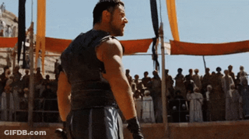 A Man Is Standing In Front Of A Crowd With A Sword GIF