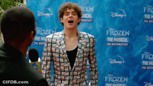 A Man Is Standing In Front Of A Disney Frozen Sign GIF