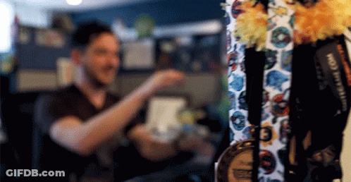A Man Is Standing In Front Of A Display Of Medals And Lanyards . GIF