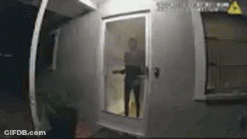 A Man Is Standing In Front Of A Door In A Room . GIF