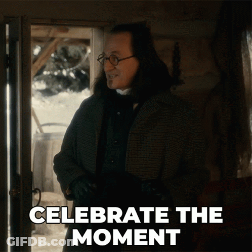 A Man Is Standing In Front Of A Door With The Words " Celebrate The Moment " Written Below Him GIF