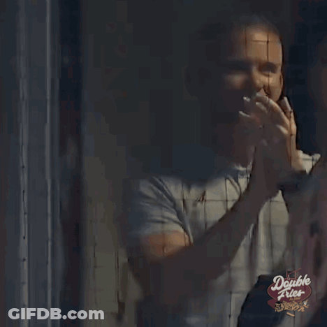 A Man Is Standing In Front Of A Double Fries Sign And Waving . GIF
