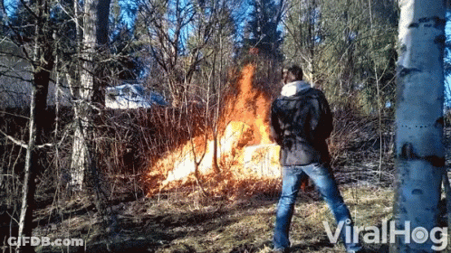 A Man Is Standing In Front Of A Fire In The Woods And The Words Viralhog Are On The Bottom GIF