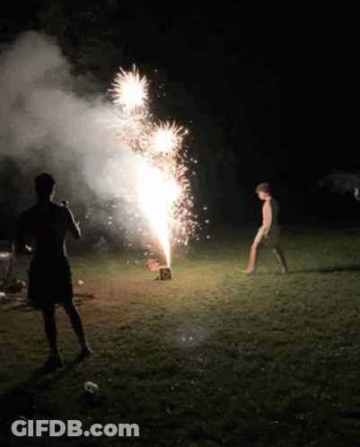 A Man Is Standing In Front Of A Firework Display With A Box That Says ' R ' On It GIF