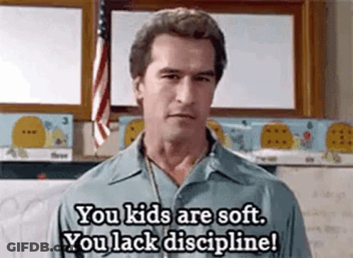 A Man Is Standing In Front Of A Flag In A Classroom And Talking To A Child . GIF