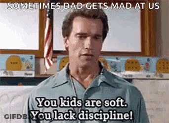 A Man Is Standing In Front Of A Flag In A Classroom And Talking To Someone . GIF