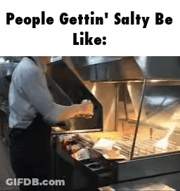 A Man Is Standing In Front Of A Fryer In A Restaurant And Cooking Food . GIF