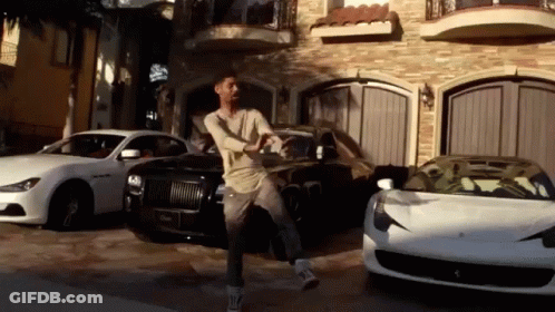 A Man Is Standing In Front Of A Garage Full Of Cars GIF